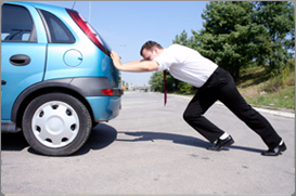 Man pushing an abandoned car.